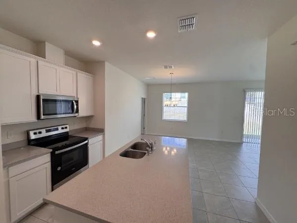 a kitchen with stainless steel appliances a sink a stove a microwave a refrigerator a counter top space and cabinets