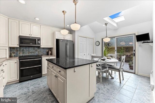 a open kitchen with stainless steel appliances granite countertop a stove top oven a sink dishwasher a dining table and chairs with wooden floor
