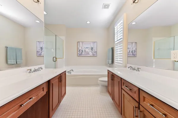 a spacious bathroom with a double vanity sink large mirror and a bathtub