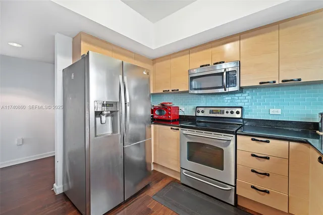 a kitchen with stainless steel appliances granite countertop a refrigerator a stove and a sink with wooden floor