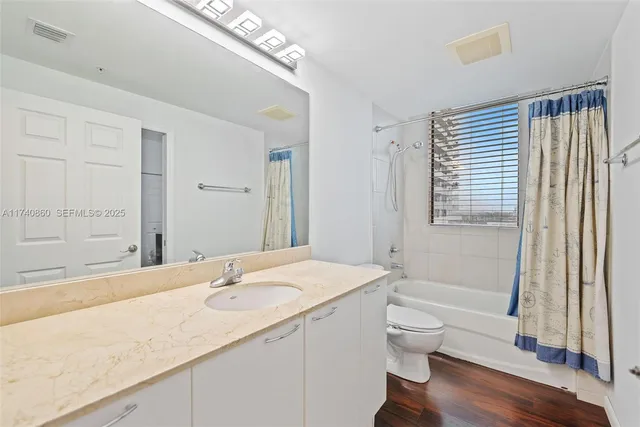 a bathroom with a granite countertop sink toilet and shower curtains