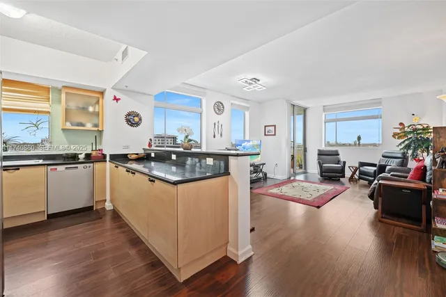 a kitchen with granite countertop a stove top oven a sink dishwasher and white cabinets with wooden floor