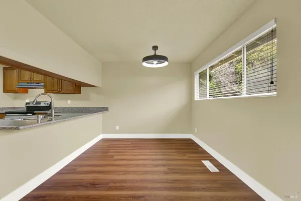 a kitchen with granite countertop wooden cabinets stainless steel appliances and a wooden floor
