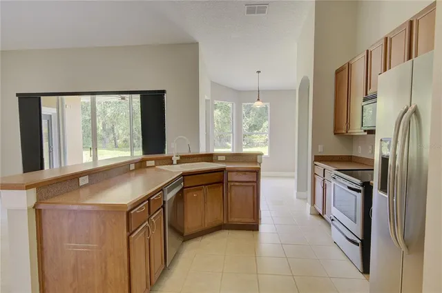 a kitchen with stainless steel appliances granite countertop a refrigerator a stove and a sink with wooden floor