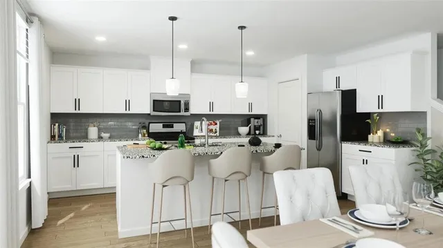 a kitchen with stainless steel appliances kitchen island granite countertop a refrigerator a stove a sink a dining table and chairs with wooden floor