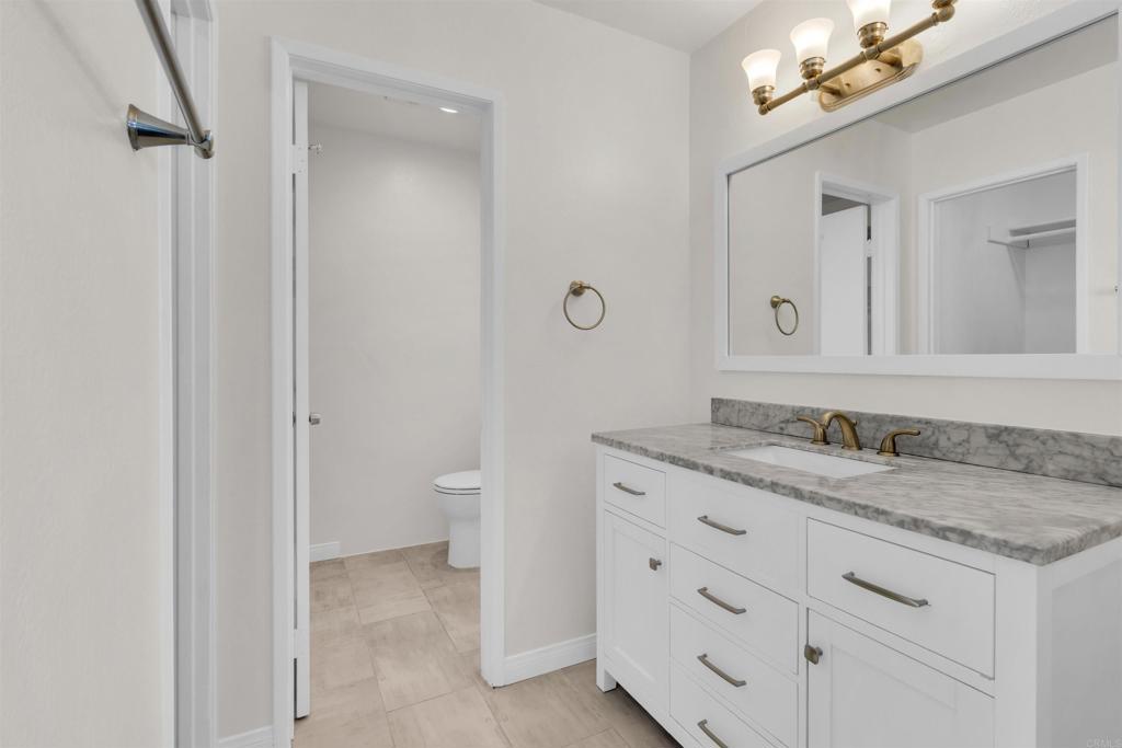 7321 Alicante Road, Unit A Carlsbad, CA 92009 - Photo 13 of 27 a bathroom with a granite countertop sink a toilet and a mirror