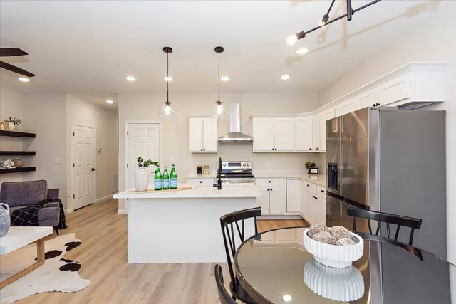 a kitchen with a refrigerator a sink a stove a dining table and chairs