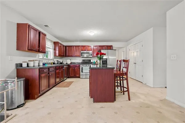 a open kitchen with stainless steel appliances granite countertop a stove top oven a sink dishwasher a dining table and chairs with wooden floor
