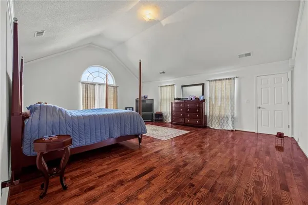 a spacious bedroom with a bed and a dresser next to a window