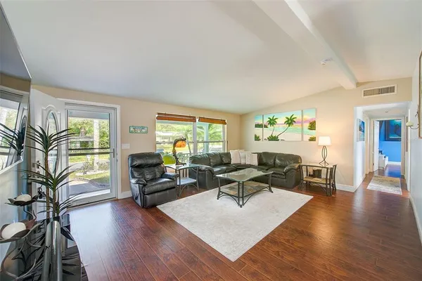 a living room with furniture large window and wooden floor