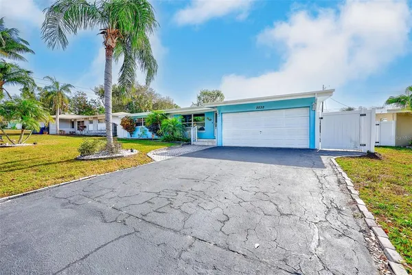 a view of a house with a yard and palm trees