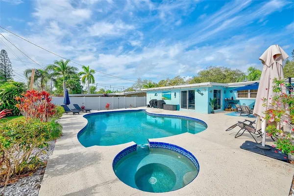 a view of a house with pool plants and chairs