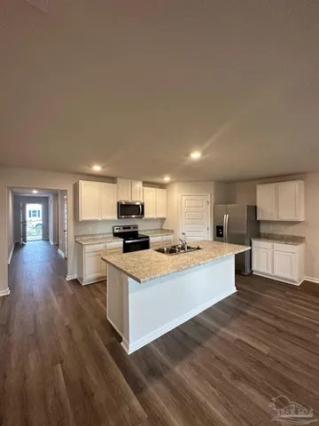 a kitchen with stainless steel appliances a stove top oven a sink dishwasher and a refrigerator with wooden floor