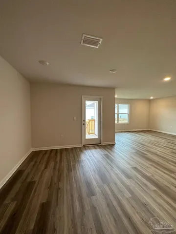 a view of an empty room with wooden floor and window