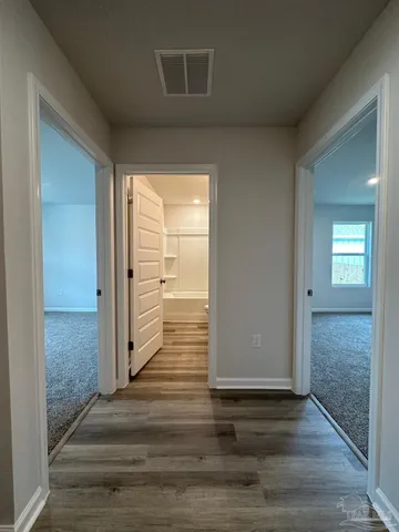 a view of a hallway with wooden floor and a living room