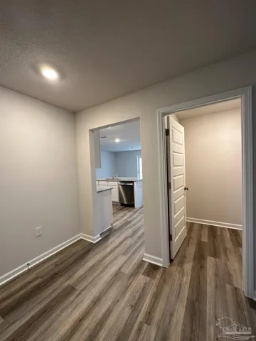 an empty room with wooden floor staircase and windows