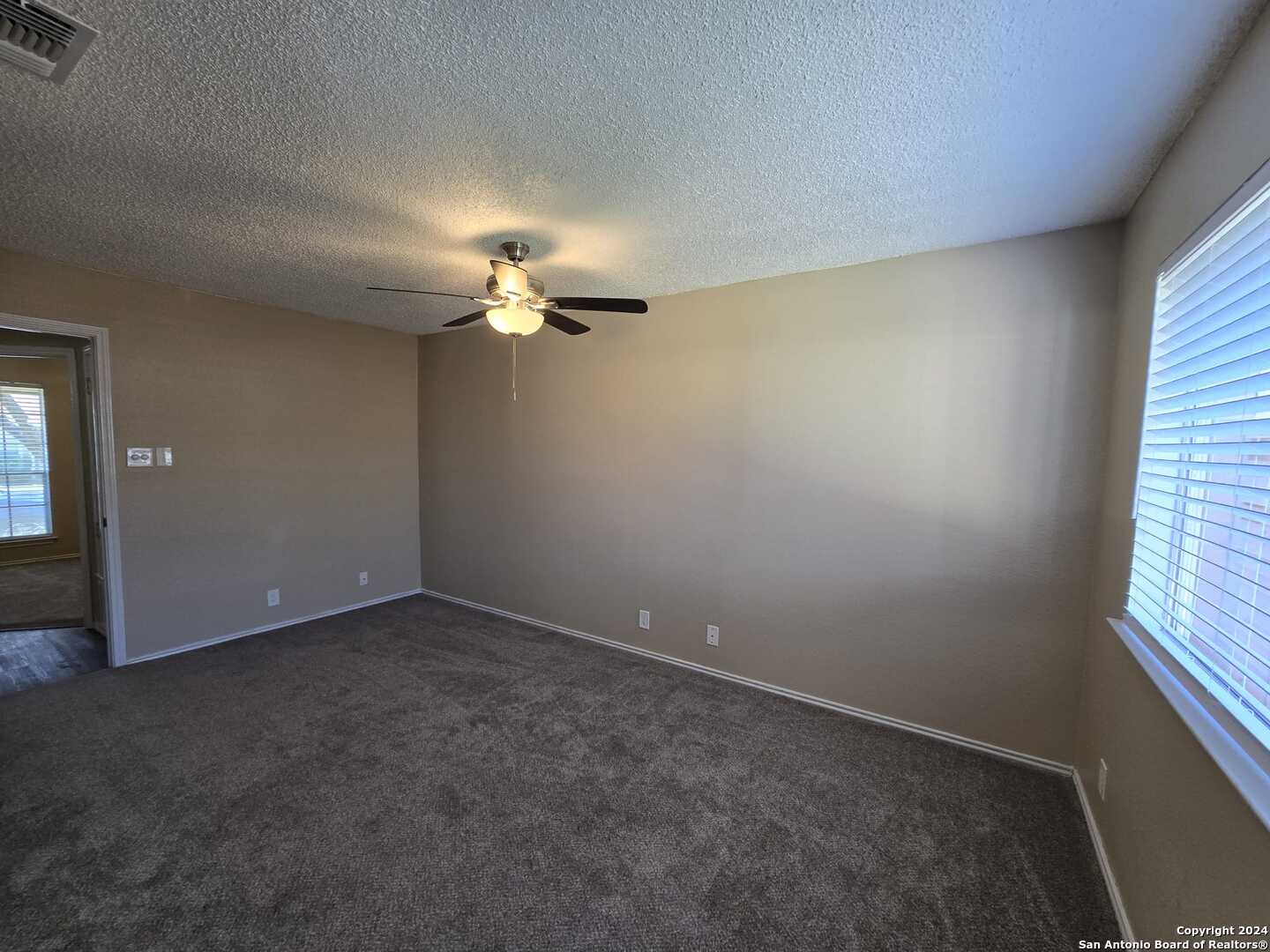 9140 Timber Path, Unit 2702 San Antonio, TX 78250 - Photo 12 of 22 en empty room with windows and chandelier fan