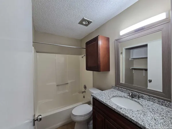a bathroom with a granite countertop sink toilet and shower