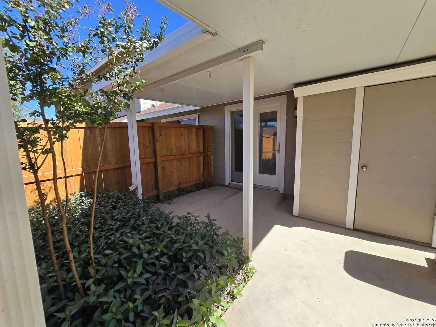 9140 Timber Path, Unit 2702 San Antonio, TX 78250 - Photo 20 of 22 a backyard of a house with a large tree and wooden fence
