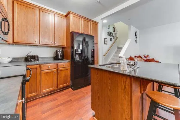 a kitchen with stainless steel appliances granite countertop a sink dishwasher stove and refrigerator with wooden floor