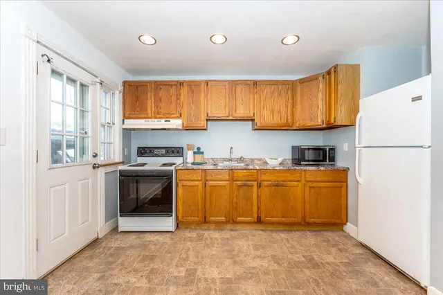 a kitchen with granite countertop a refrigerator stove top oven and sink
