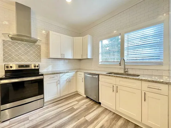 a kitchen with granite countertop white cabinets stainless steel appliances and a sink