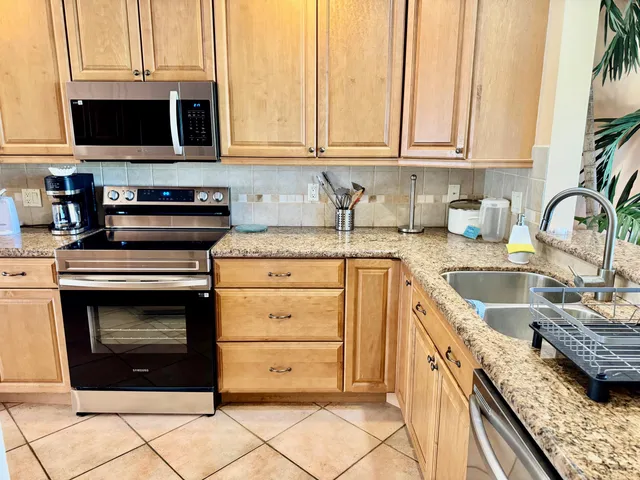 a kitchen with granite countertop a stove top oven microwave and cabinets