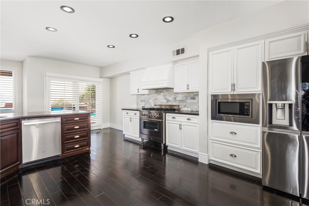 1608 Smiley Ridge Redlands, CA 92373 - Photo 24 of 84 a kitchen with stainless steel appliances white cabinets and wooden floor