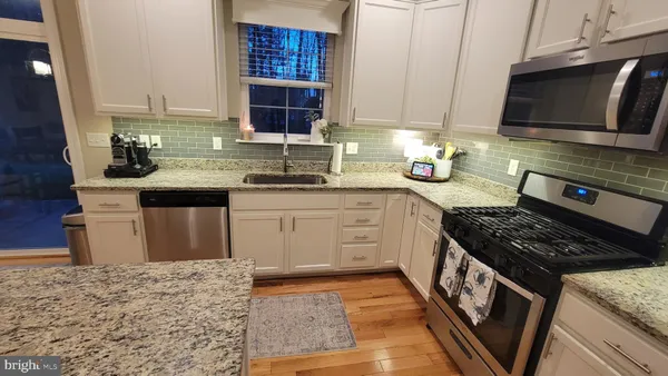 a kitchen with stainless steel appliances granite countertop a refrigerator stove microwave and sink