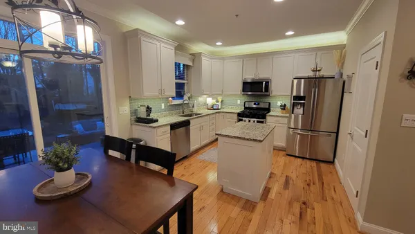 a kitchen with granite countertop kitchen island stainless steel appliances refrigerator dining table and chairs