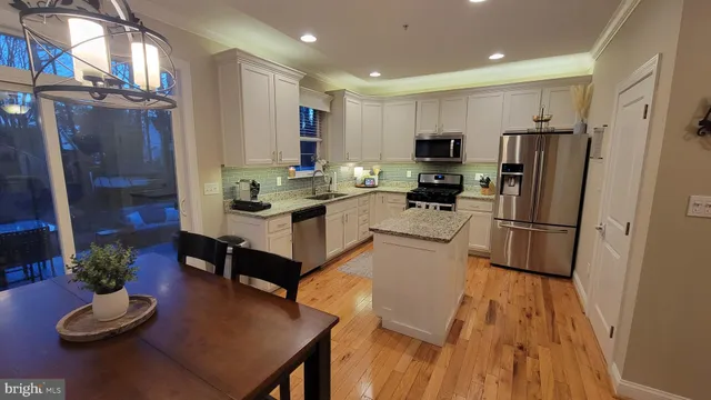 a kitchen with granite countertop kitchen island stainless steel appliances refrigerator dining table and chairs