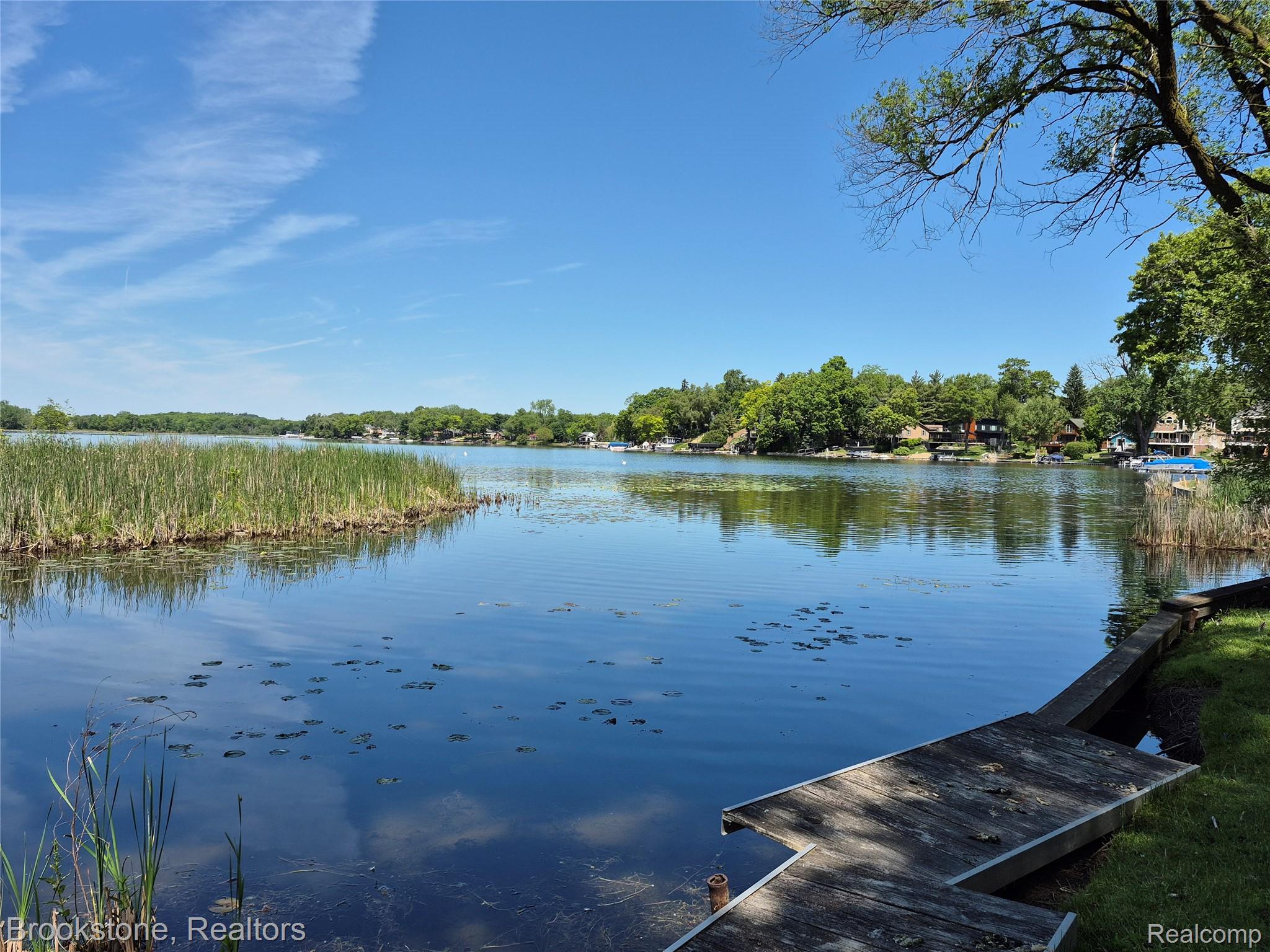 4295 Sashabaw Road Waterford, MI 48329 - Photo 5 of 37 Waterfront property featuring a private wooden dock, lush green grass, and mature trees framing the lake