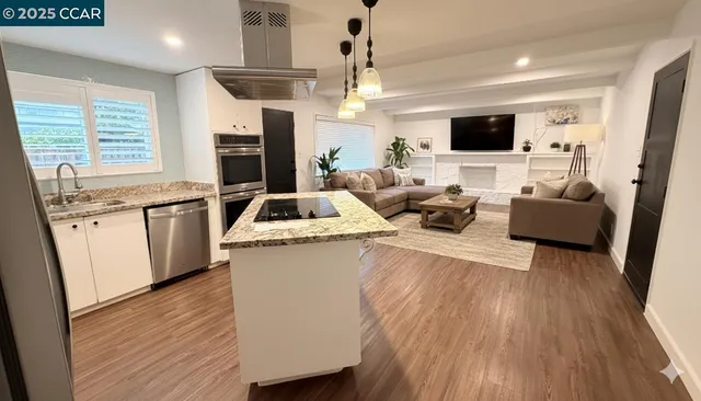 a living room with stainless steel appliances furniture and a flat screen tv