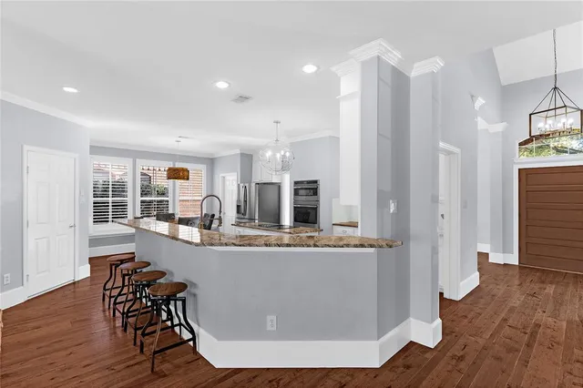 a living room with stainless steel appliances kitchen island granite countertop furniture and wooden floor