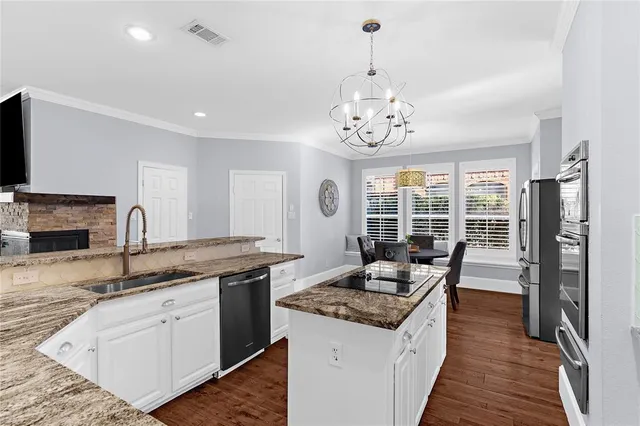 a kitchen with a stove top oven a sink dishwasher a dining table and chairs with wooden floor