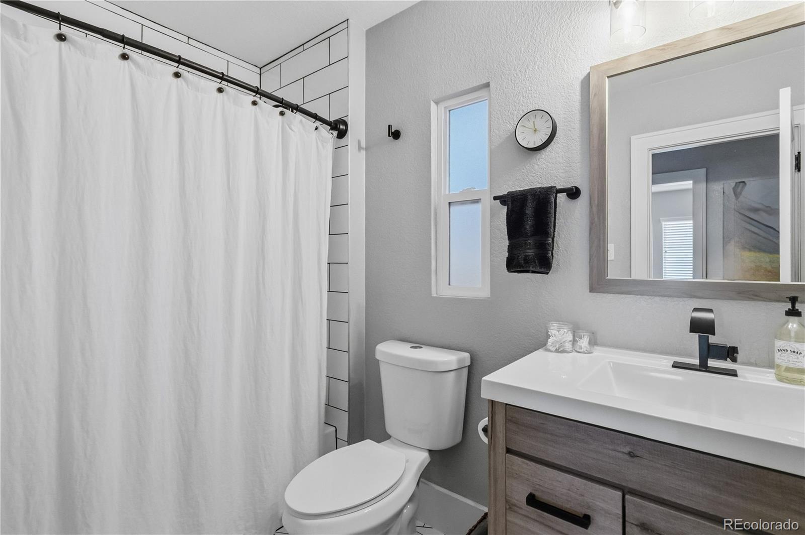 1620 Galena Street Aurora, CO 80010 - Photo 16 of 34 a bathroom with a sink a toilet a mirror and shower curtain