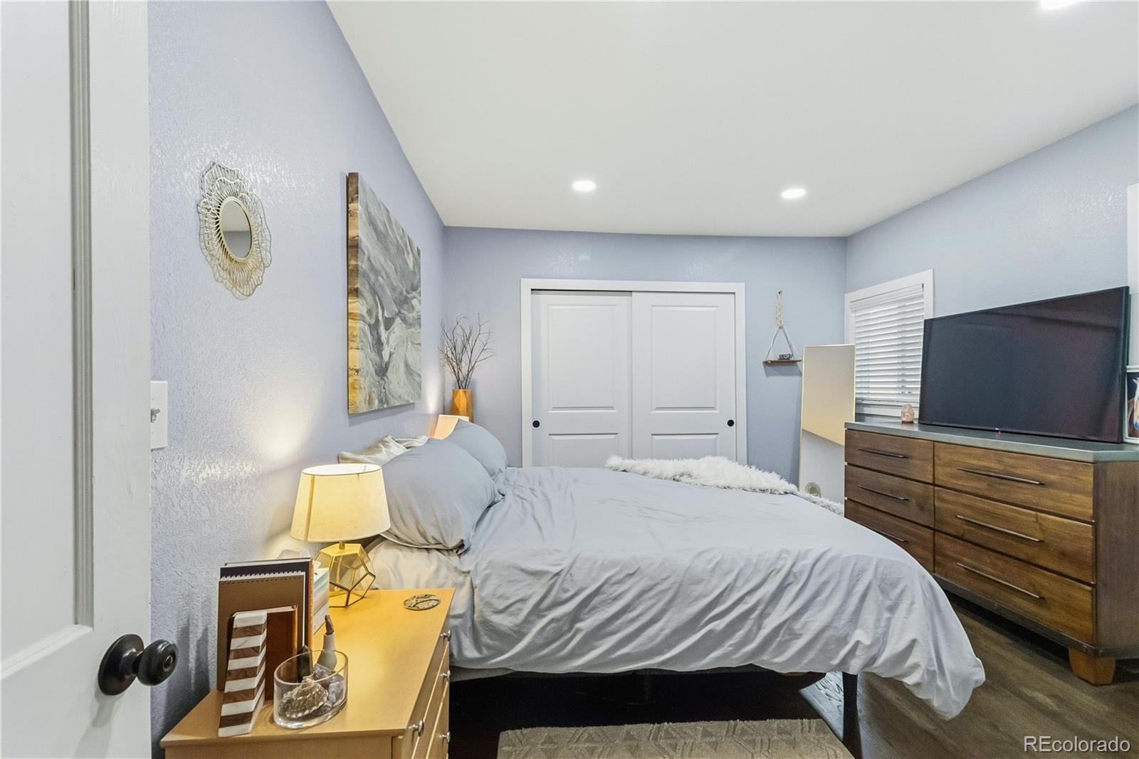 1620 Galena Street Aurora, CO 80010 - Photo 20 of 31 a bedroom with a bed and flat tv screen on the dresser