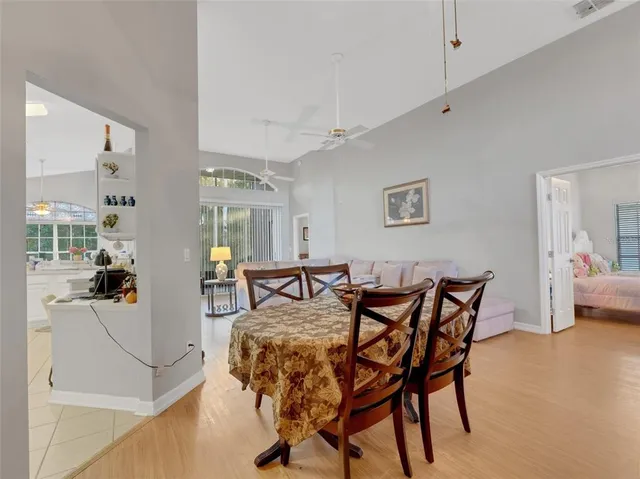 a view of a dining room and livingroom with furniture wooden floor a rug a flat screen tv a painting and a chandelier
