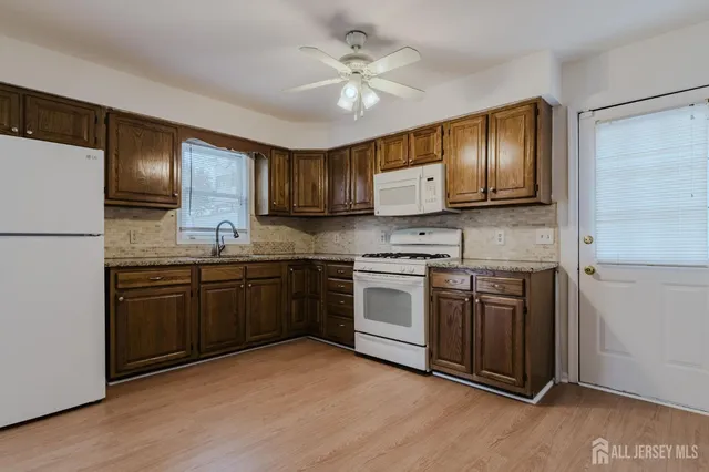 a kitchen with granite countertop a refrigerator stove top oven and sink