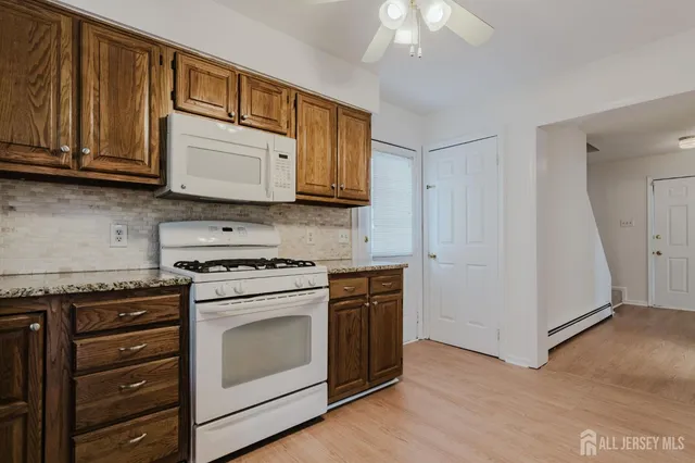 a kitchen with granite countertop wooden cabinets and white appliances
