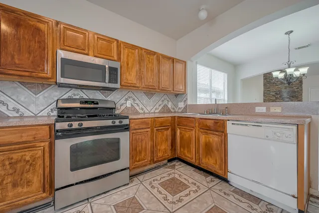 a kitchen with stainless steel appliances granite countertop a stove a sink and a microwave