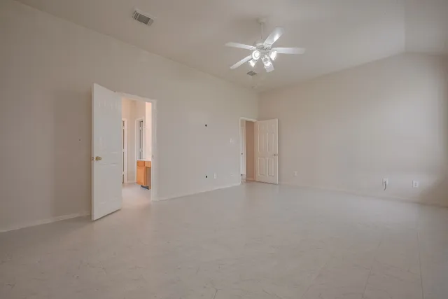 a view of an empty room with a chandelier fan