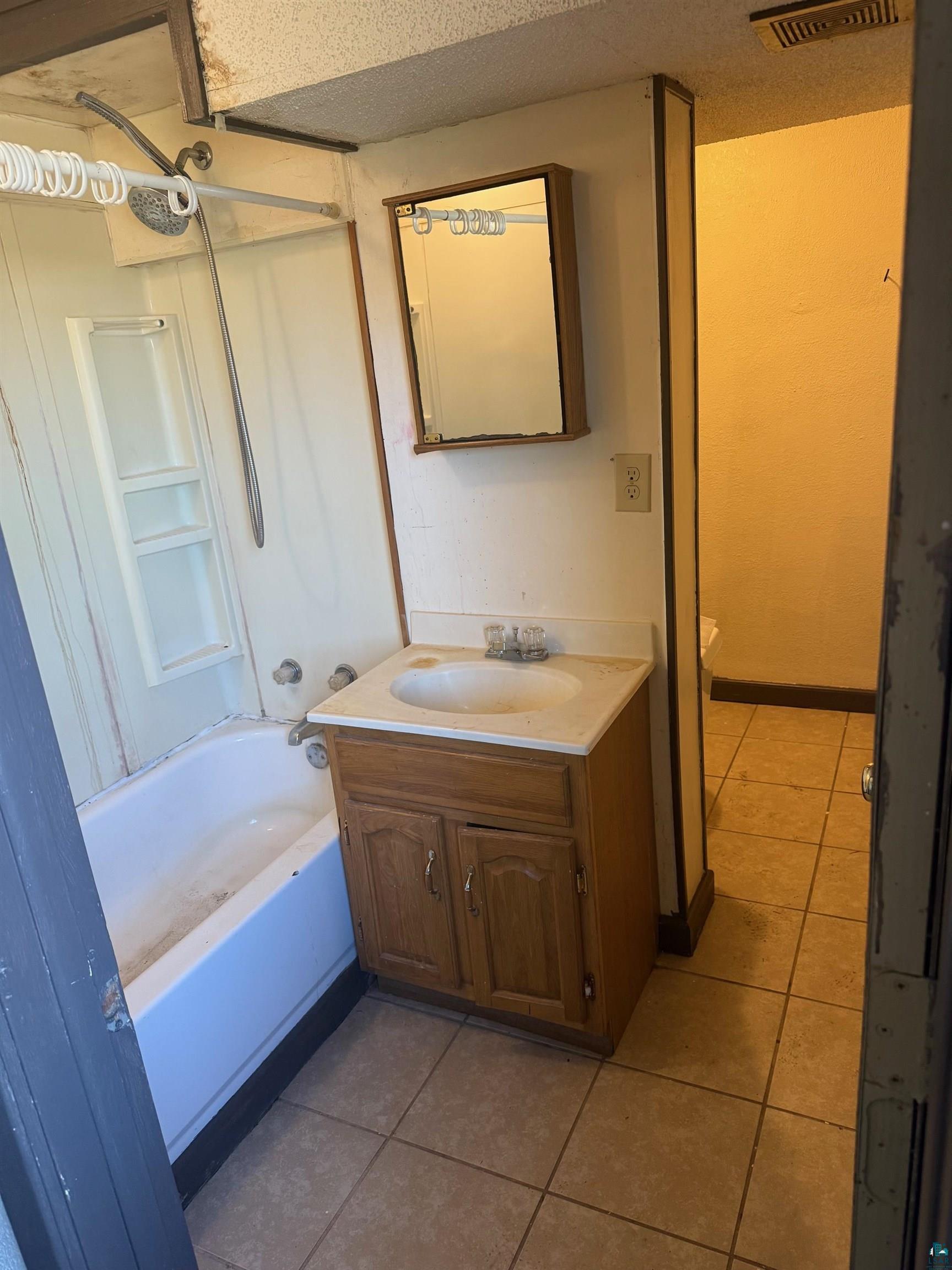 801 East 41st Street Hibbing, MN 55746 - Photo 3 of 5 Full bathroom with vanity, tile patterned flooring, shower / bathtub combination, and visible vents