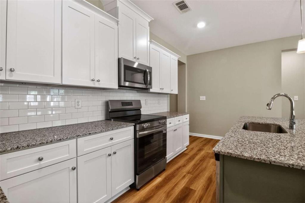 103 Gnome Court Perry, GA 31069 - Photo 13 of 30 a kitchen with granite countertop white cabinets and stainless steel appliances