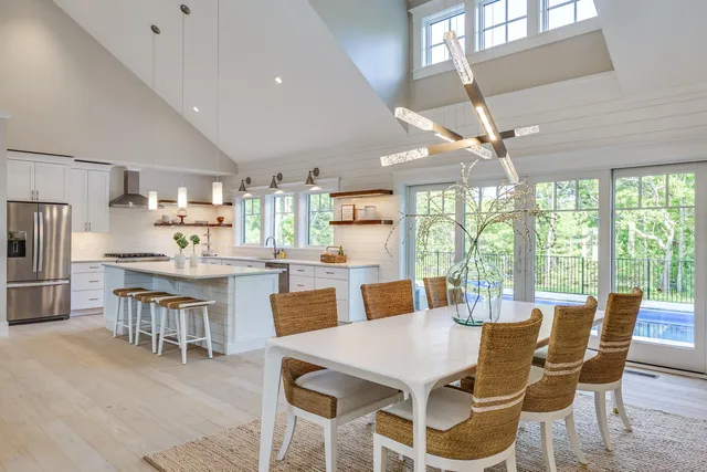 a kitchen with stainless steel appliances a stove a sink a refrigerator white cabinets and wooden floor