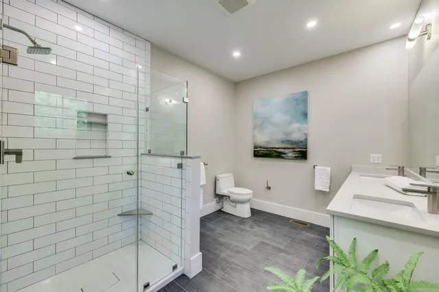 a spacious bathroom with double vanity a mirror and a shower