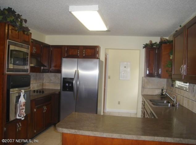 54346 Dornbush Road Callahan, FL 32011 - Photo 4 of 12 a kitchen with stainless steel appliances granite countertop a refrigerator a stove and a sink with wooden floors