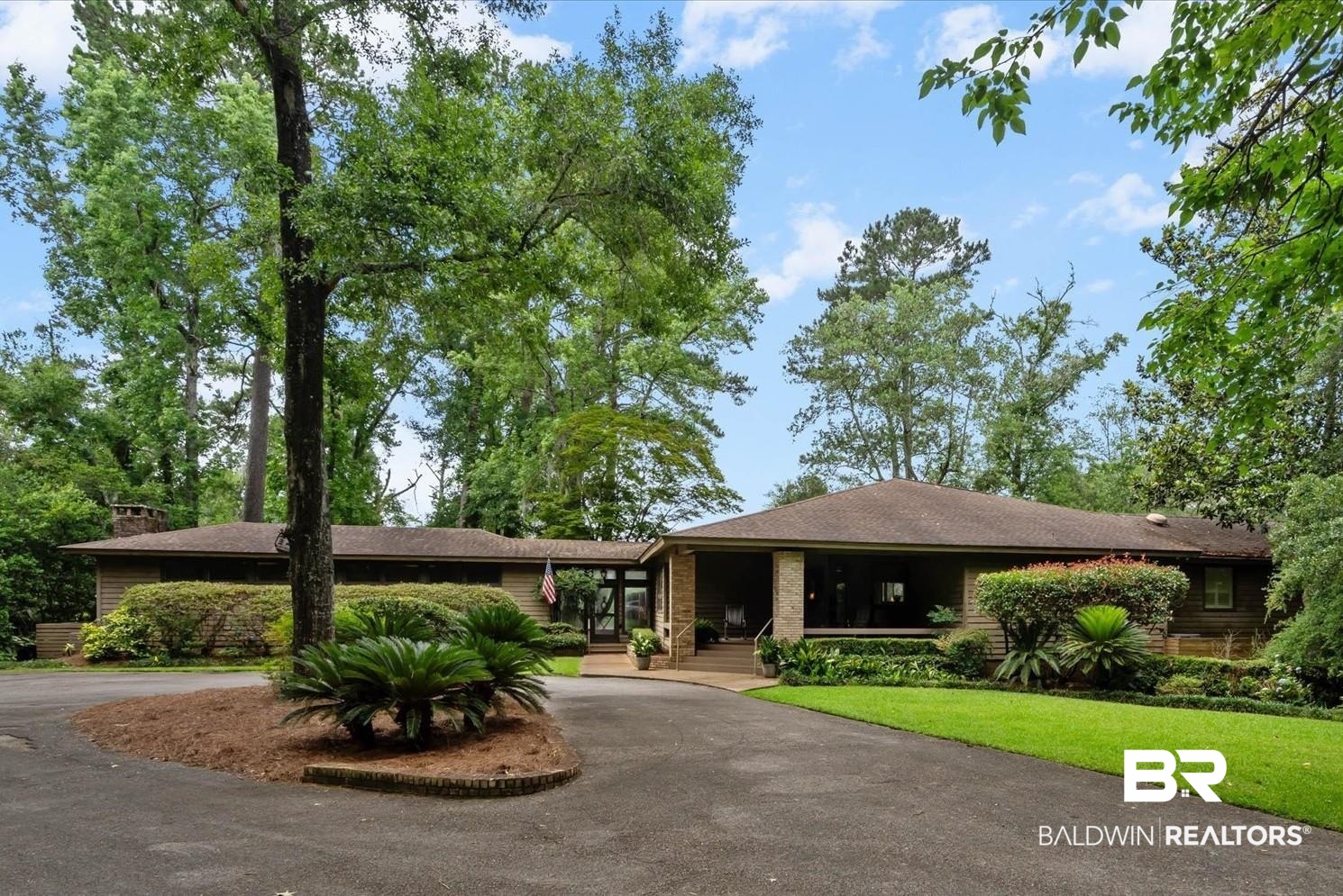 3500 Venetia Road Mobile, AL 36605 - Photo 1 of 56 Ranch-style residence featuring a paved circular driveway, mature trees, manicured landscaping, a covered front porch, and an attached garage with a glass door