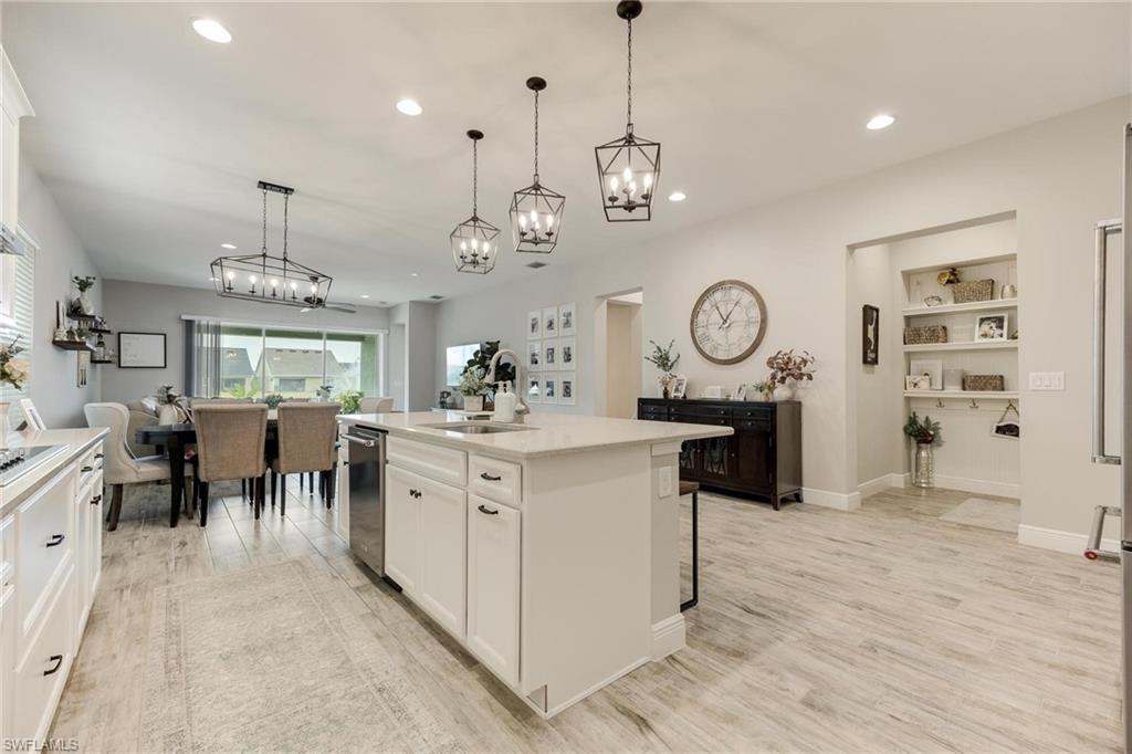 3621 Pilot Circle Naples, FL 34120 - Photo 15 of 46 an open kitchen with a refrigerator a sink dishwasher a dining table and chairs with wooden floor