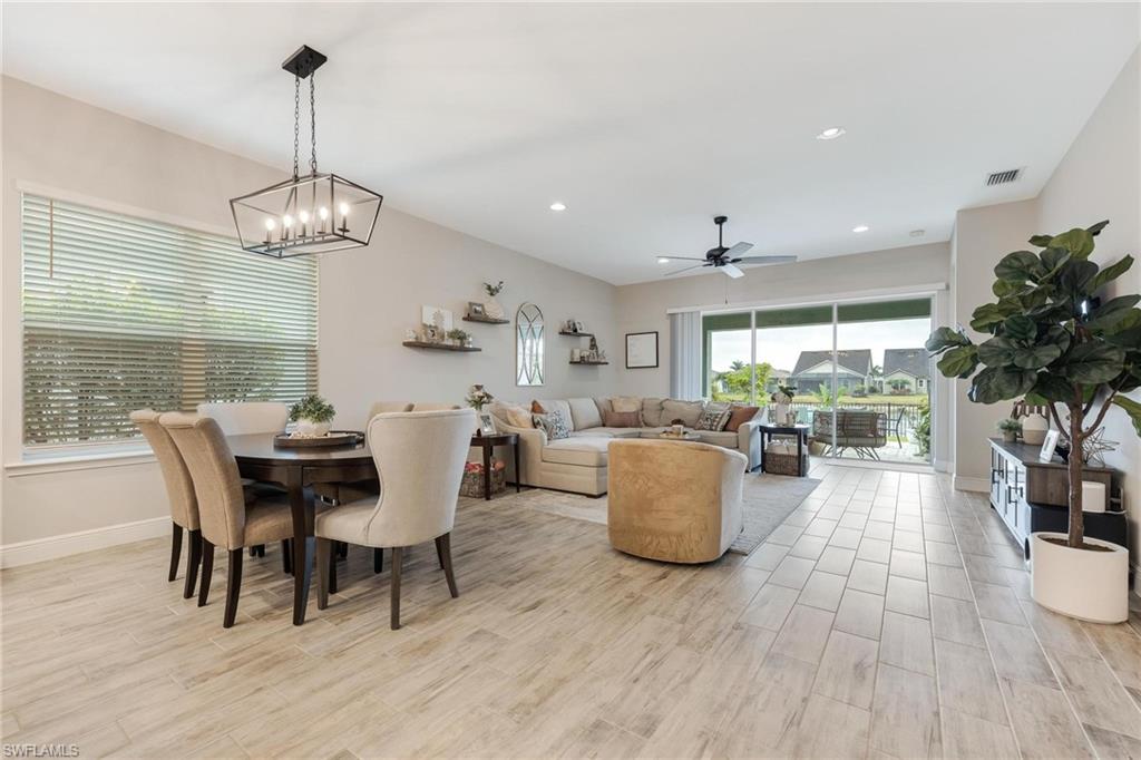3621 Pilot Circle Naples, FL 34120 - Photo 17 of 46 a dining room with wooden floor a chandelier a wooden table and chairs